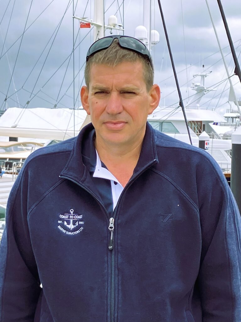 Heath Mabbett standing on a pier with a yacht in the background